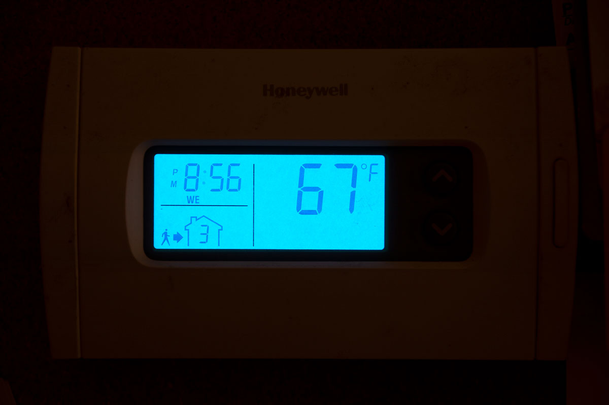 Image of a backlit thermostat control panel showing 67 degrees.